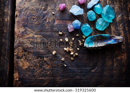 Treasure hunting. Mining for gems. Gold and gems on rough wooden surface. Royalty-Free Stock Photo #319325600
