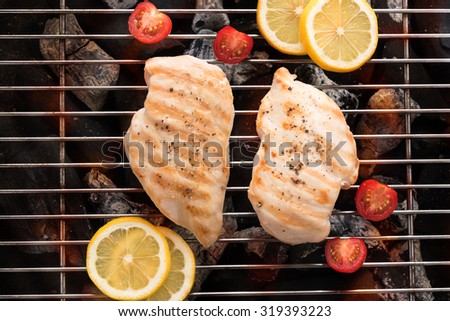 Grilled chicken breast on the flaming grill.