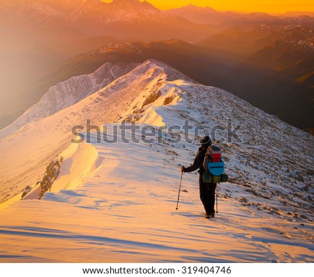Beautiful amazing sunset winter mountains.  A man goes a sport hike in snow holidays. Christmas background. Unique landscape. Northern country Russia Caucasus.