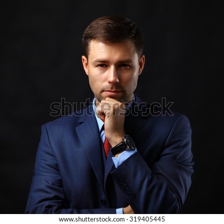 Handsome young business man standing on black background