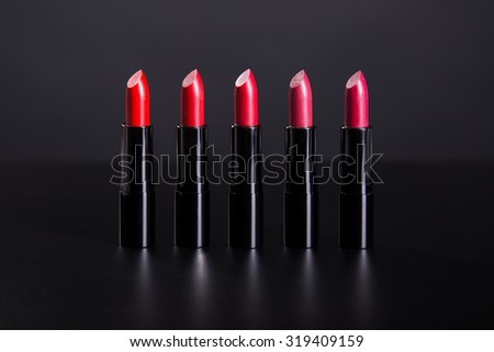Set of bright lipsticks in shades of red color, studio shot on black background 
