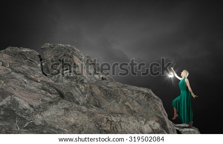Young woman in green dress with lantern in darkness