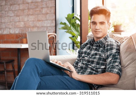 Businessman using laptop on sofa in coffee shop