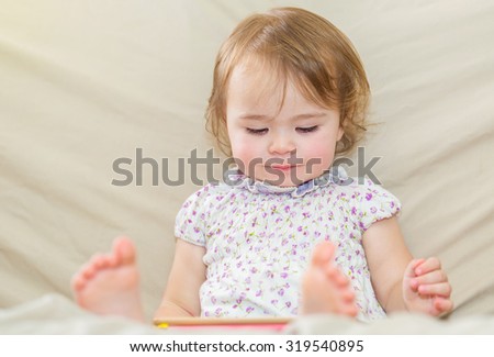 Happy toddler girl watching cartoons on her tablet computer