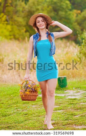 Young girl in a straw hat with a basket of wild flowers in the autumn