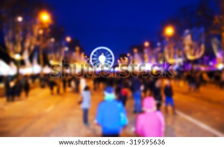 Blurred photo of people promenade at Champs Elysees with Christmas festive illumination and ferris wheel at Place de la Concorde seen at background. Paris in winter. 