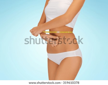 people, beauty, weight loss and diet concept - close up of woman with tape measuring her waist
