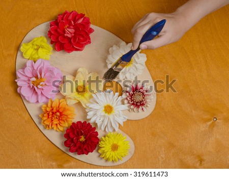 autumn flowers of bright flowers on a palette together with a brush
