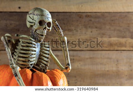 Skeleton is saluting on pumpkin and blur background.Halloween holiday concept.copy space for creative design.