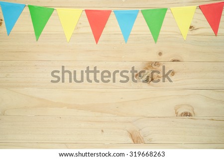  A line of colourful party flags on wooden background with space for text
