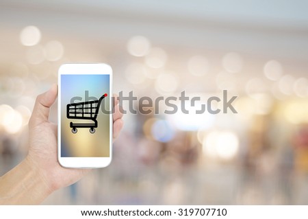 Hand holding mobile on shopping mall blur background , background concept design
