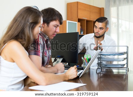 Serious bank employee trying hard to make young couple pay back a loan