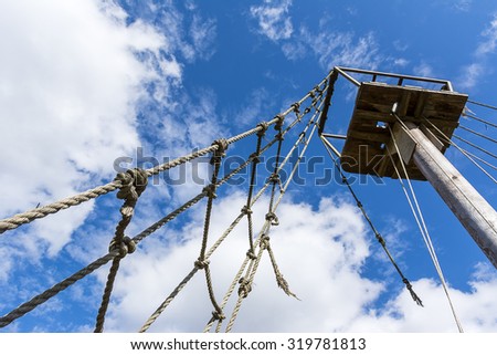 Old rope ladder and mast against cloudy sky