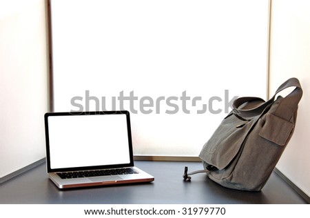 Laptop open on desk with carrier bag blank screen for editing