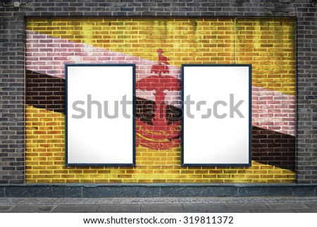 Two blank billboards attached to a buildings exterior brick wall which has a Brunei flag painted on it.