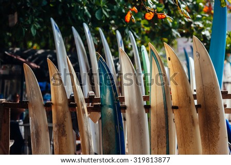 Set of different color surf boards in a stack by ocean. WELIGAMA. Surf boards on sandy Weligama beach in Sri Lanka. On Weligama beach surf is available all year around for beginner and advanced. Royalty-Free Stock Photo #319813877