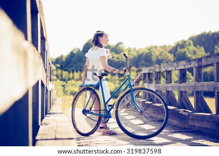 Beautiful girl with a bicycle on the bridge.