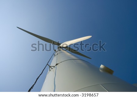 Looking up at a three-bladed wind turbine. Low angle shot.