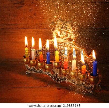 Image of jewish holiday Hanukkah background with menorah (traditional candelabra) and Burning candles with glitter overlay
