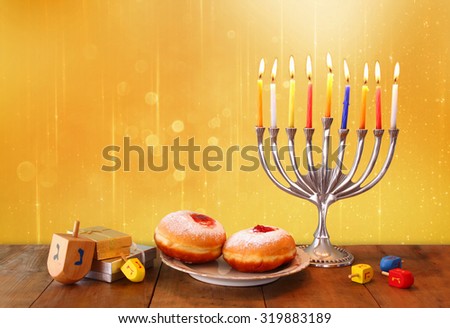 image of jewish holiday Hanukkah with menorah (traditional Candelabra), donuts and wooden dreidels (spinning top). glitter background
