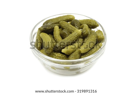 some pickled cucumbers in a glass bowl on a white background