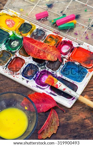 set of different paint colors and  brush for painting on wooden background in the autumn style