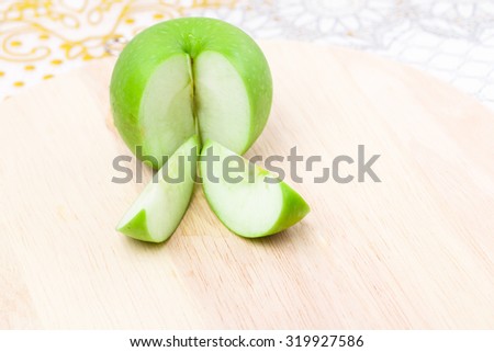 Green apple split two pics on block wood.