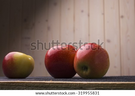 Closeup of three fresh ripe delicious beautiful fruits with vitamins of red and yellow apple lying on wooden background, horizontal picture