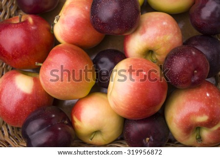 Natural colorful background of many fresh tasty ripe clear fruits of yellow red apple and purple plum lying in heap, horizontal picture