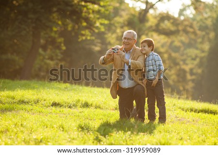 Grandfather and grandson photographing nature in park Royalty-Free Stock Photo #319959089