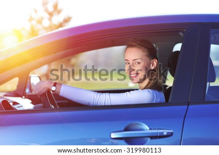 Happy woman in new blue car