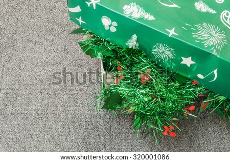 Pile of christmas decoration in a green box on gray carpet background