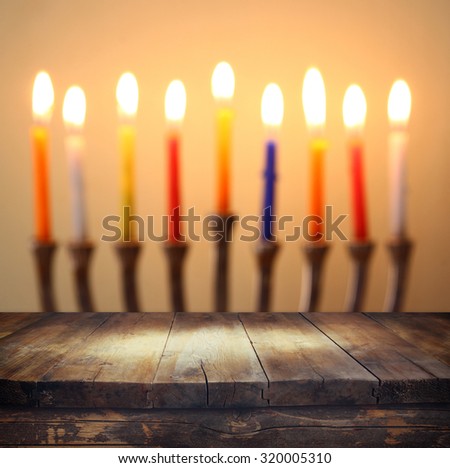 Image of jewish holiday Hanukkah background with menorah (traditional candelabra) Burning candles over wooden table 
