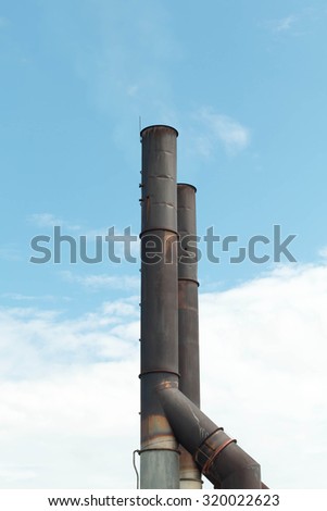 Two old factory smokestack tube against the cloudy sky