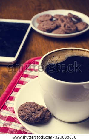 Cup of coffee with mobile phone and cookies on a wooden table