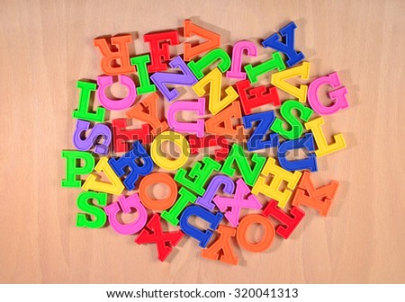 Heap of plastic colored alphabet letters on a wooden background