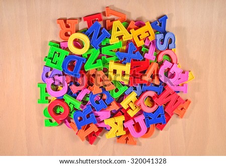 Heap of plastic colored alphabet letters on a wooden background 
