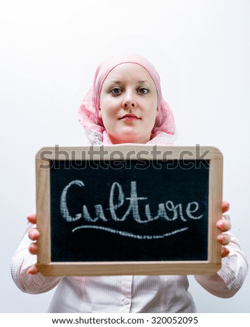 Young caucasian women dressed in pink arab clothes holding blackboard with culture word in hands
