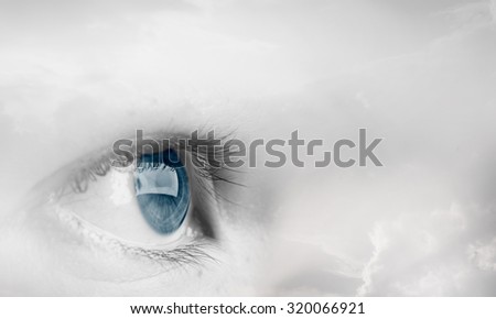 Female blue eye on cloudy sky background 