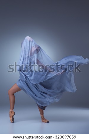 The beautiful ballerina dancing in long blue dress on blue background