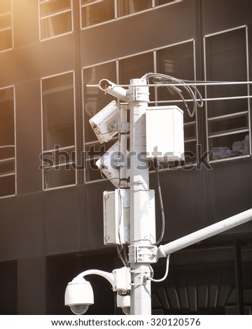 A security video surveillance camera is high in the sky with a city building in the background for a safety concept
