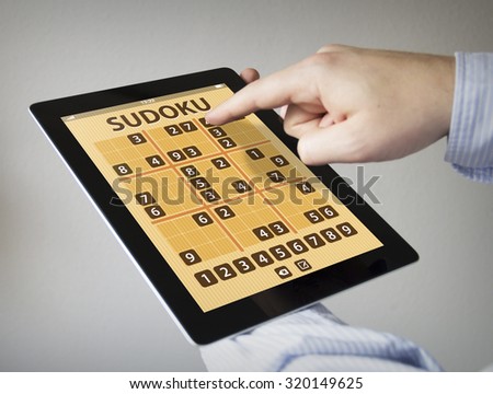 hands with touchscreen tablet with sudoku game aplication

