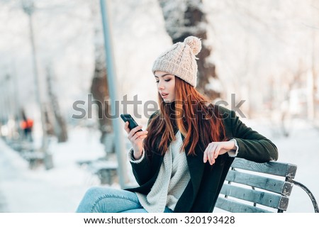 Young  woman smiling with smart phone and winter landscape 
