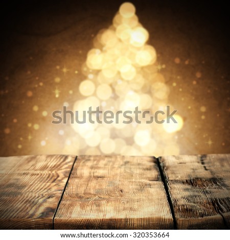 blurred background of xmas tree in golden colors and wooden desk space 