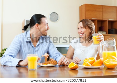 Happy couple having breakfast with scrambled eggs and oranges juice in morning together