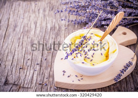 Herbal butter for breakfast with lavender flowers in a white ceramic cup with a wooden spoon on the wooden background with a bouquet of fragrant cut lavandly. selective Focus