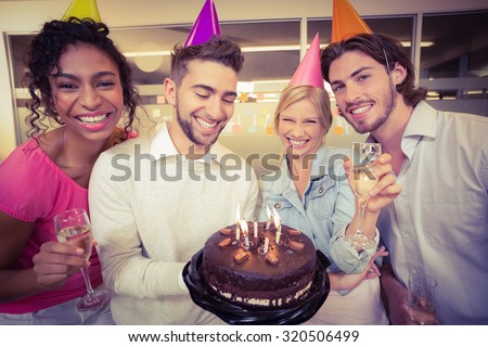 Portrait of smiling business people with birthday cake enjoying the party in creative office
