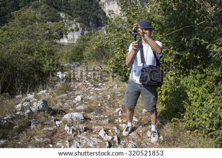 Photographer shooting landscape with small action camera. Made with shallow depth of field.