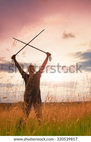 Happy girl  hiker with crossed poles in evening meadow