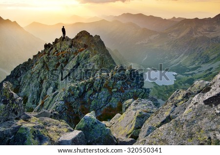 Man on the top of the hill watching wonderful scenery in mountains during summer colorful sunset in High Tatras in Slovakia Royalty-Free Stock Photo #320550341